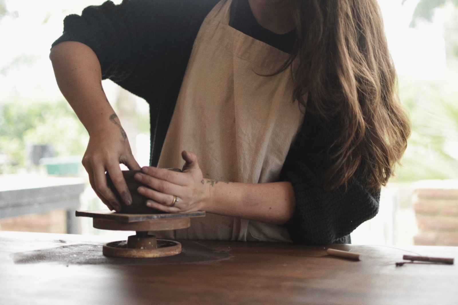 Hands shaping a clay vessel on a banding wheel